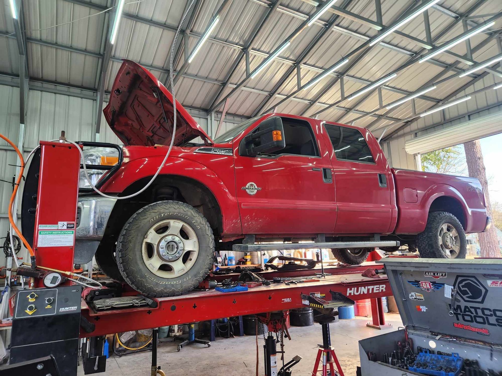 A red truck is sitting on top of a lift in a garage.