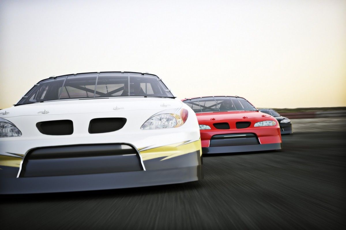 Three race cars are racing down a track.