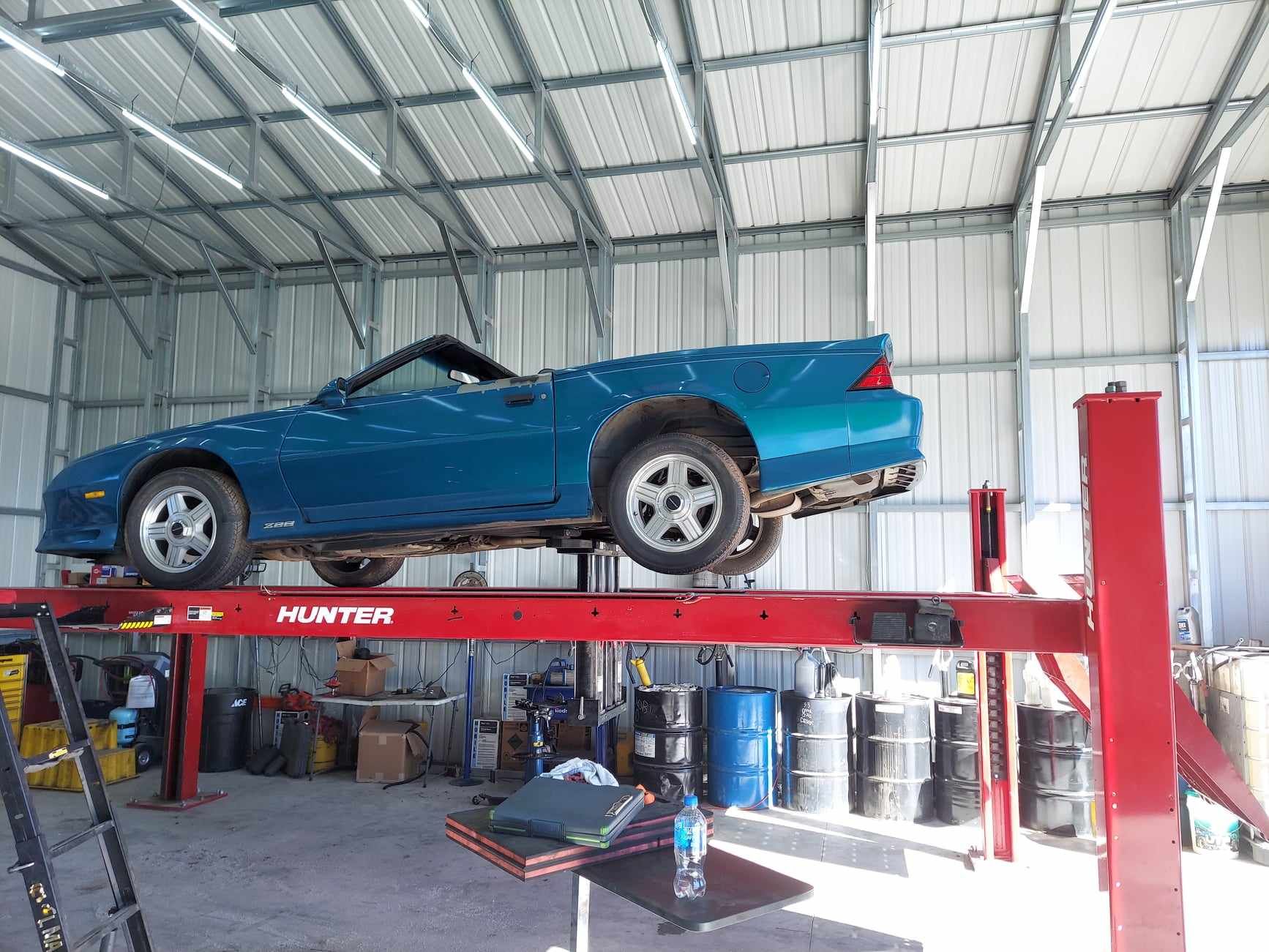 A blue car is sitting on top of a red lift in a garage.