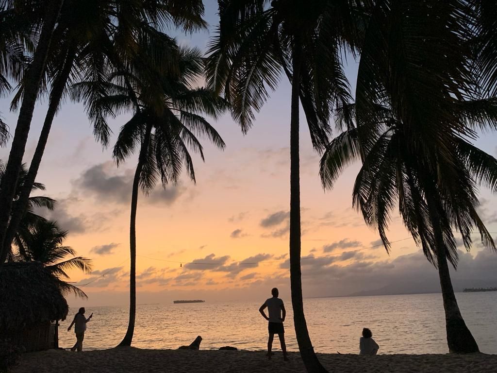 a sunset on a beach with palm trees in the foreground on franklin island san blas