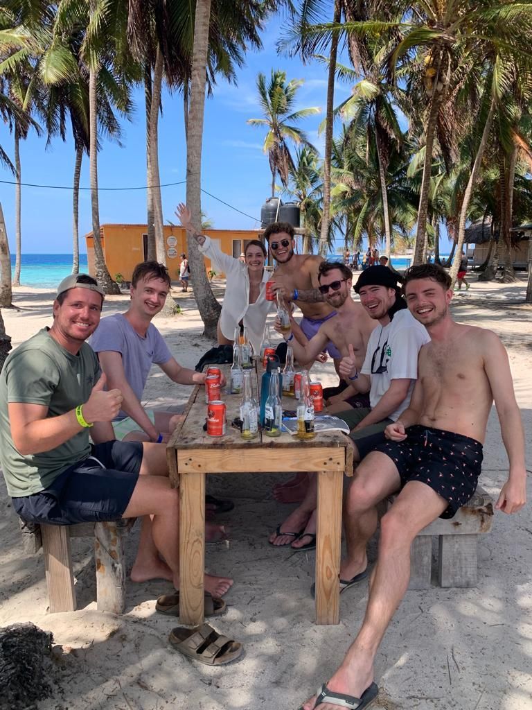 A group of men are sitting around a table on the beach.