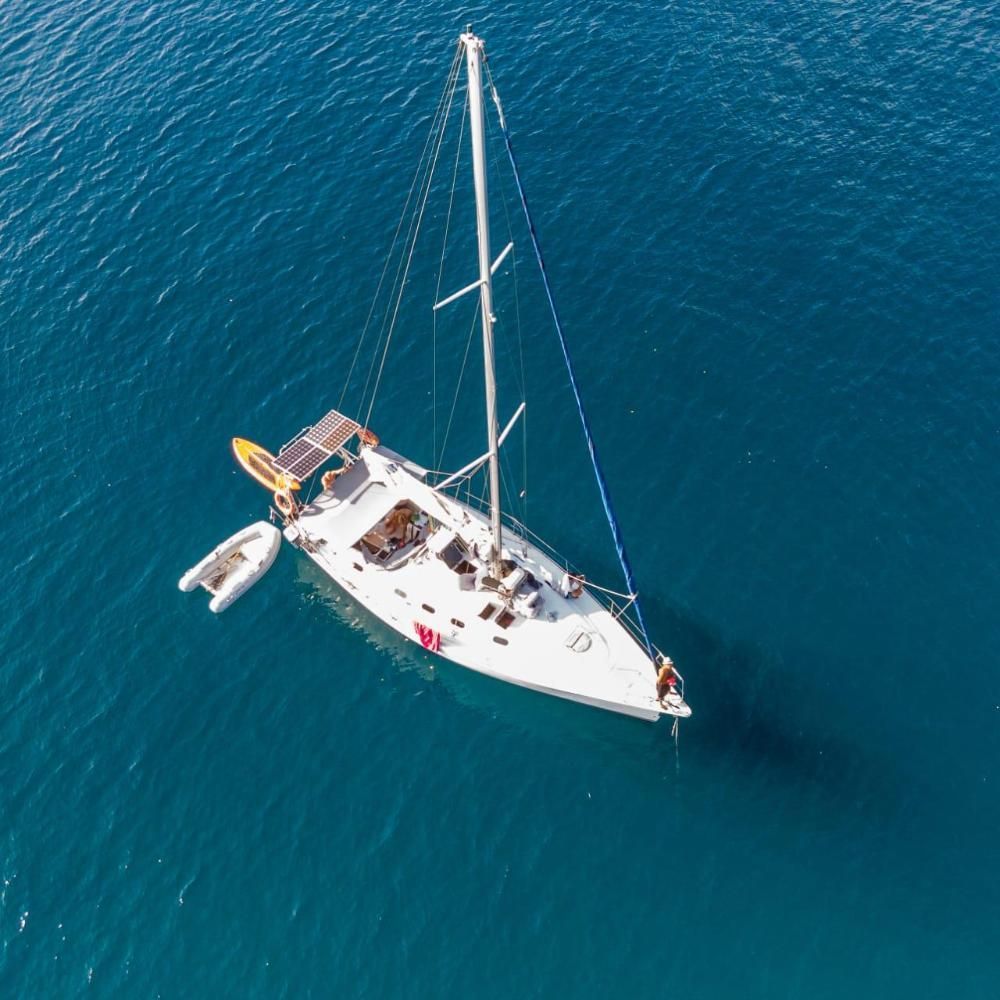 An aerial view of a sailboat in the ocean.