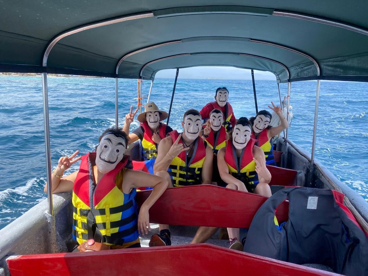 A group of people wearing life jackets and masks are on a boat in the ocean near pelicano island san blas