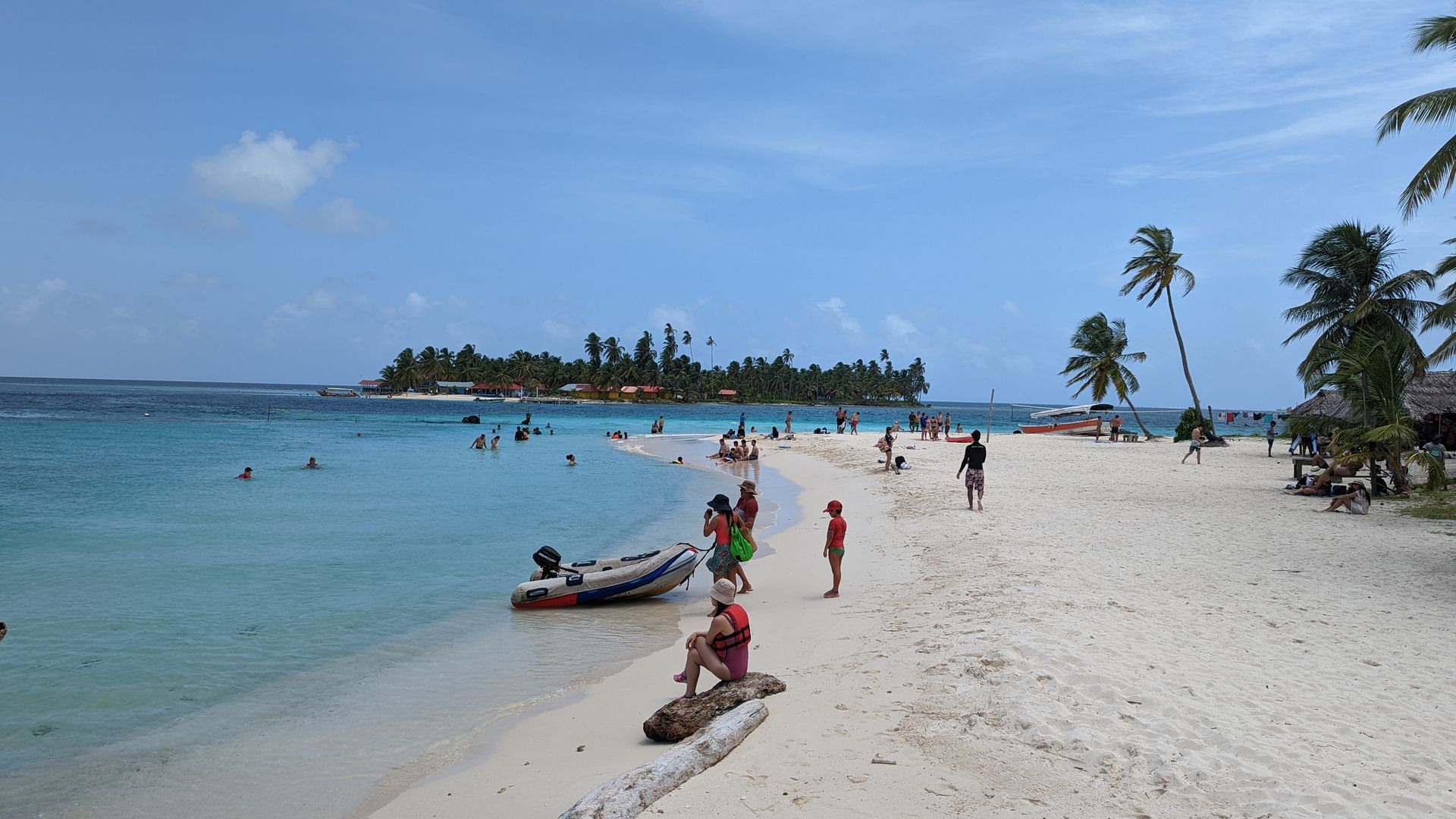 a group of people are on a beach and in the water on perro chico island
