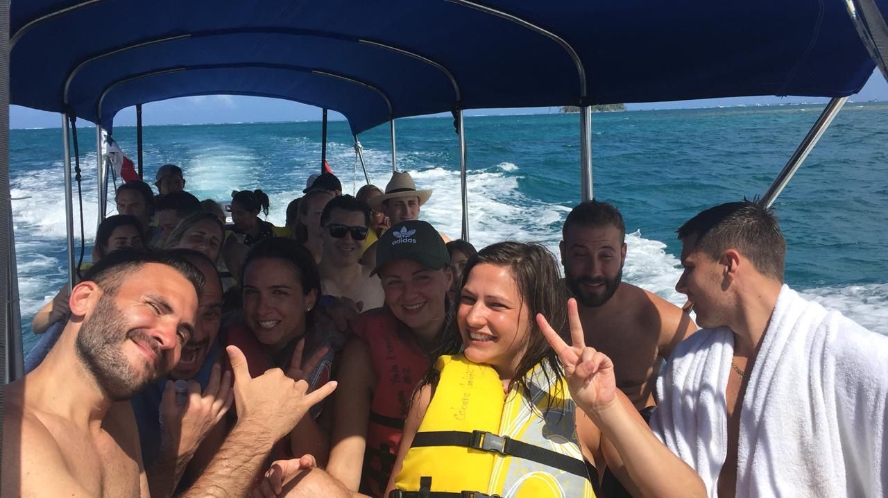 a group of people are sitting on a boat in san blas smiling going to yanis island