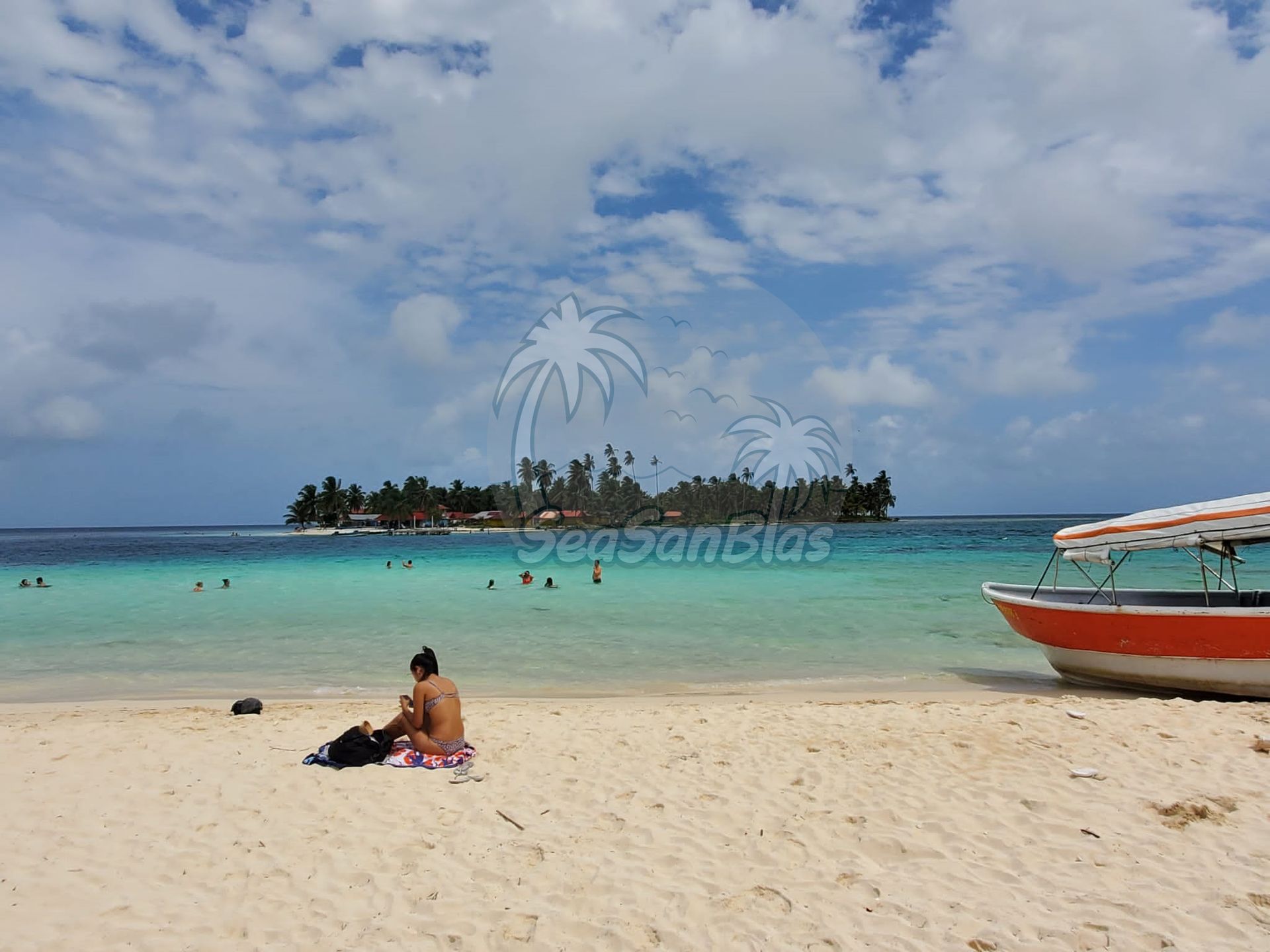A man sits on the beach next to a boat San Blas Islands Guna Yala San Blas Tours