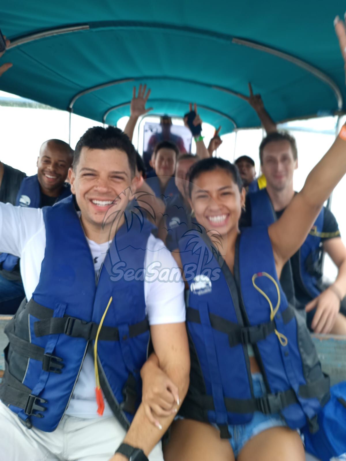 a group of people on a boat with one man wearing a vest that says s on it
