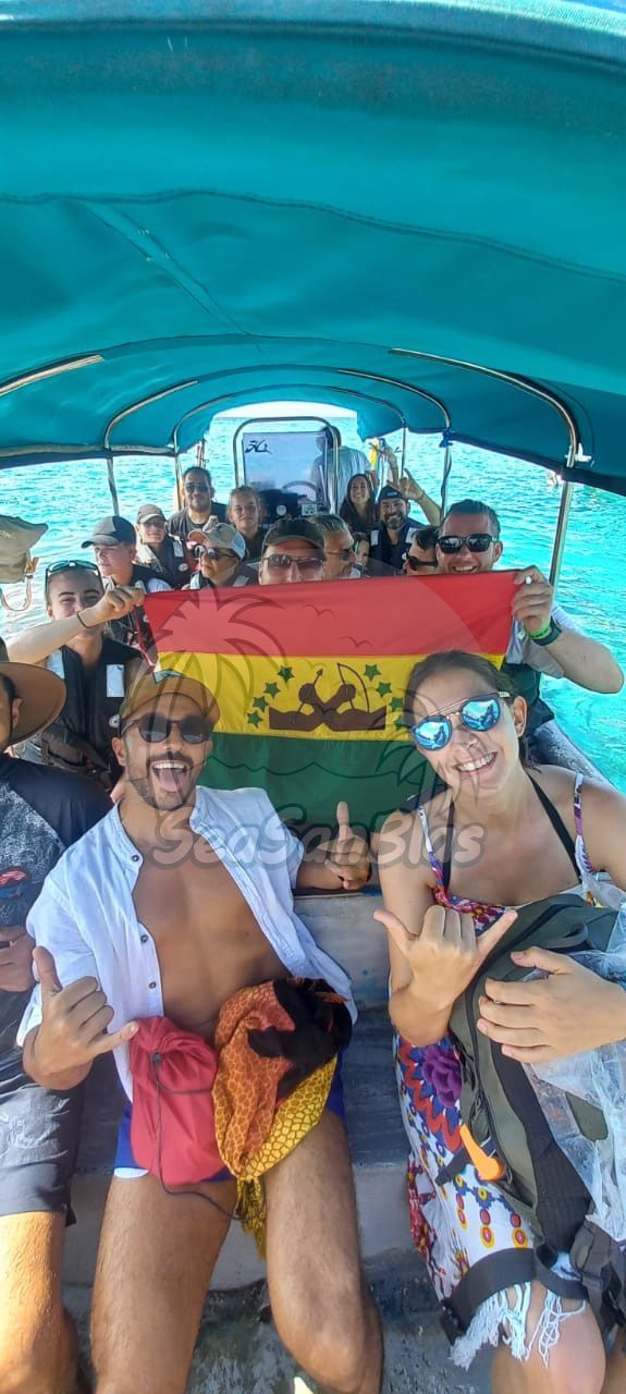 A group of people are sitting on a boat holding a flag.