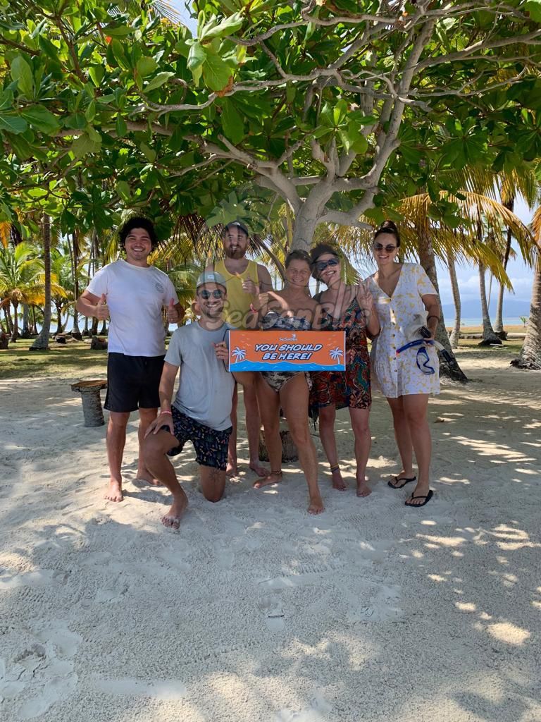 A group of people are standing on a beach holding a sign.