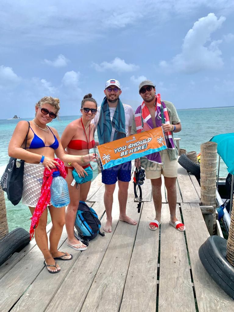 A group of people are standing on a dock holding a sign.