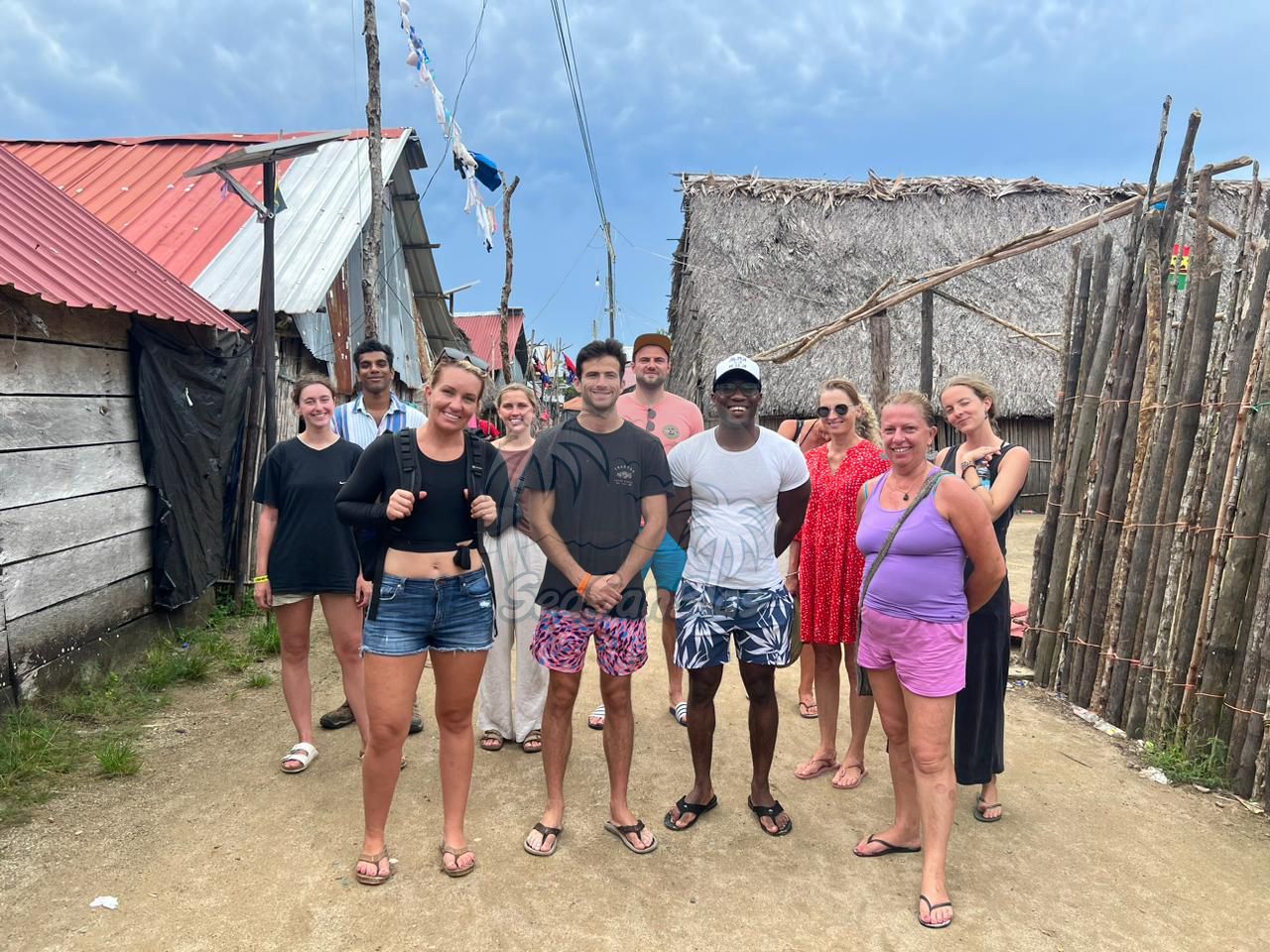 a group of people standing in front of a thatched building