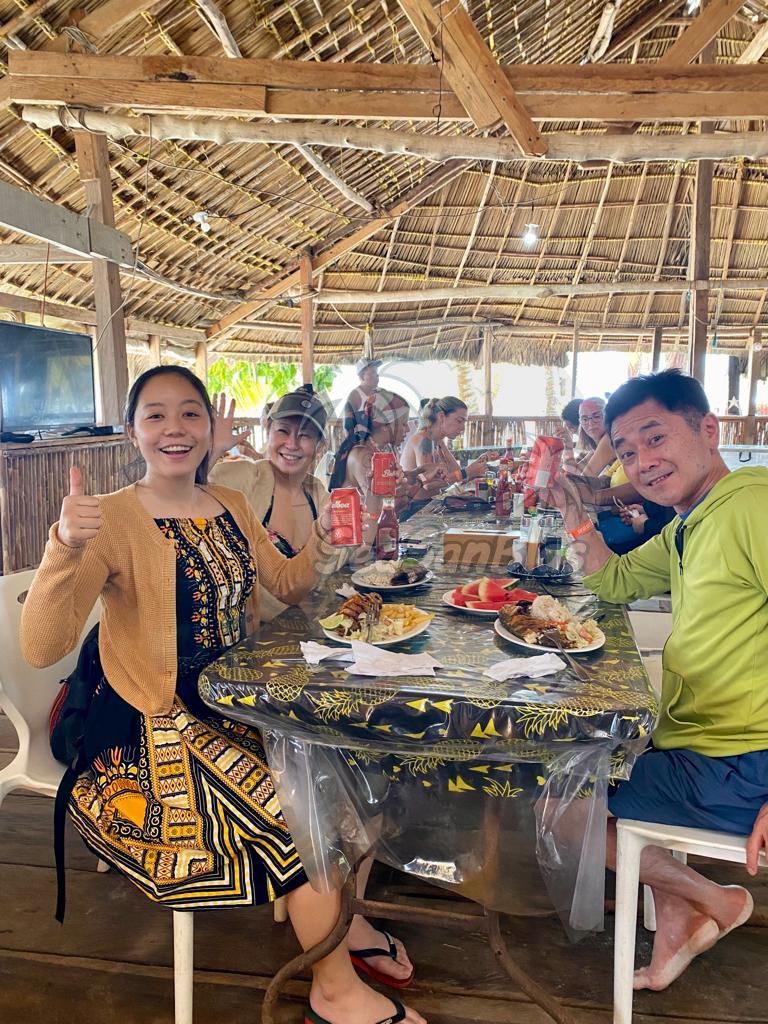 A group of people are sitting at a table eating food. San Blas Islands Guna Yala San Blas Tours