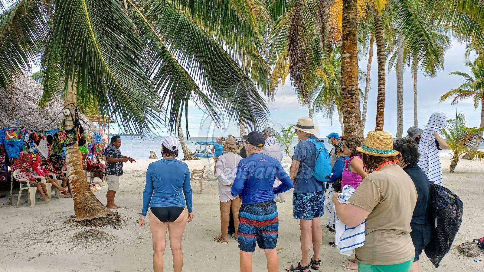 A group of people are standing on a beach under palm trees. San Blas Islands Guna Yala San Blas Tours