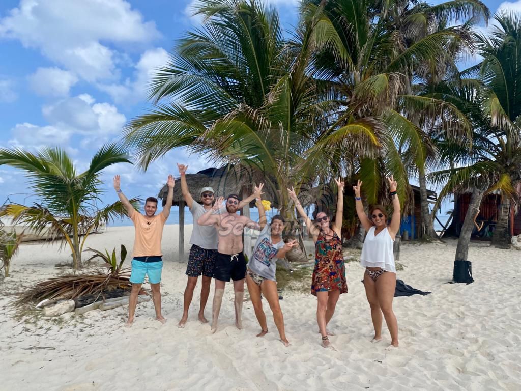 A group of people are standing on a beach with their arms in the air.