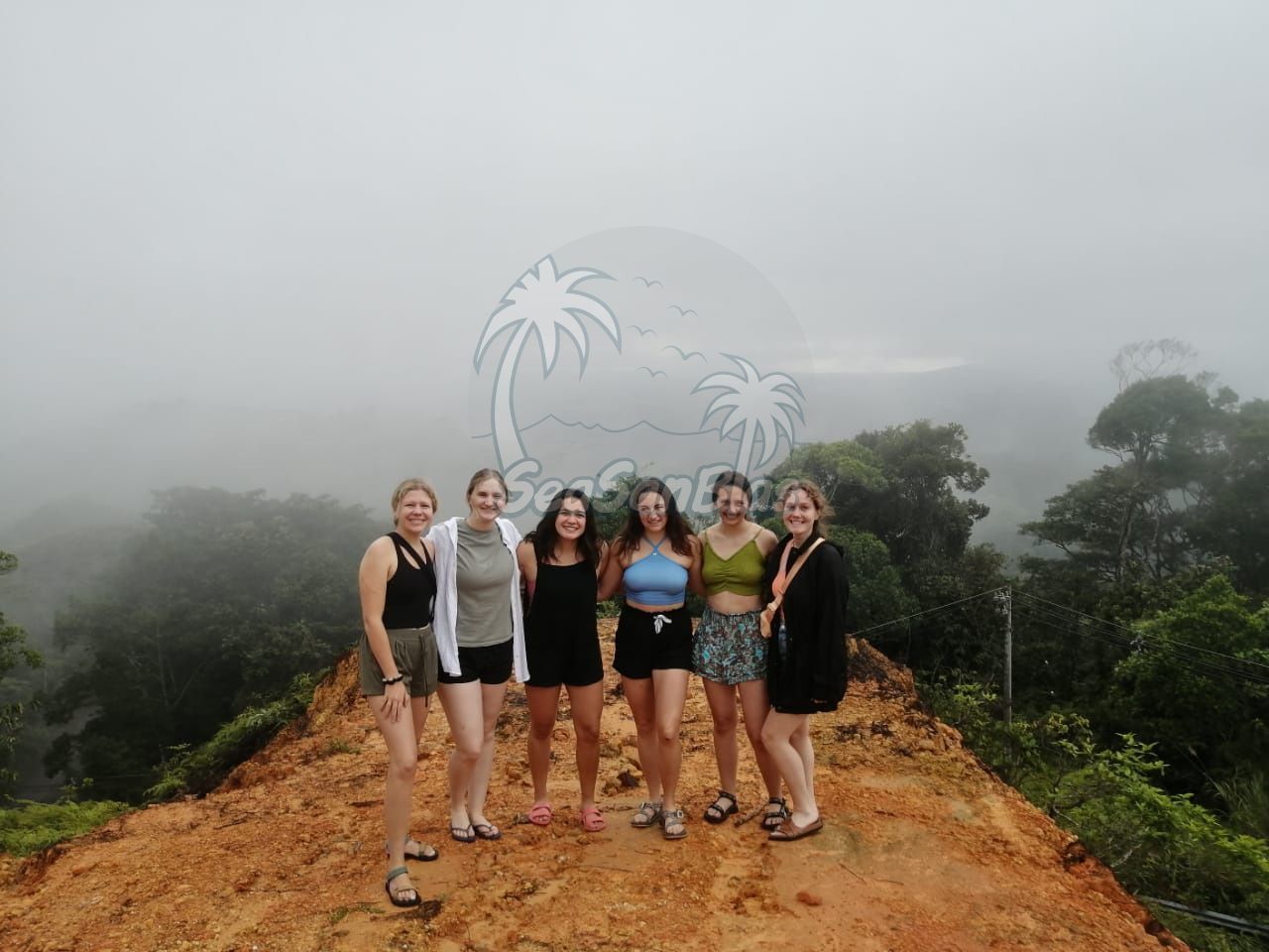 A group of women are posing for a picture on a dirt road.