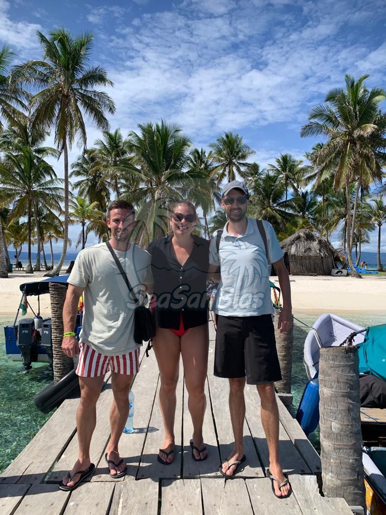 Three people are posing for a picture on a dock near a beach. San Blas Islands Guna Yala San Blas Tours