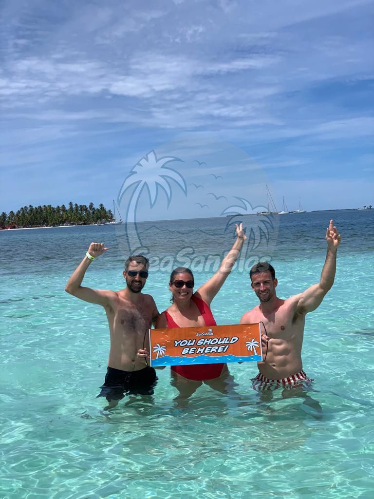 Three people are standing in the water holding a sign. San Blas Islands Guna Yala San Blas Tours