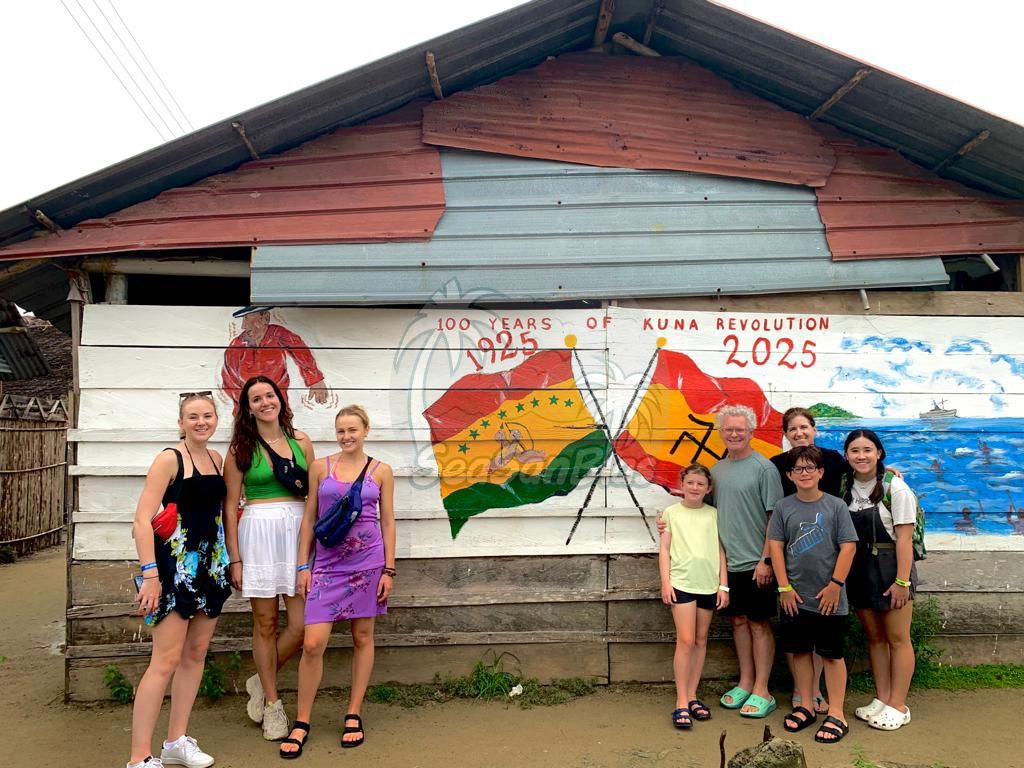 A group of people are standing in front of a painting on a wall.