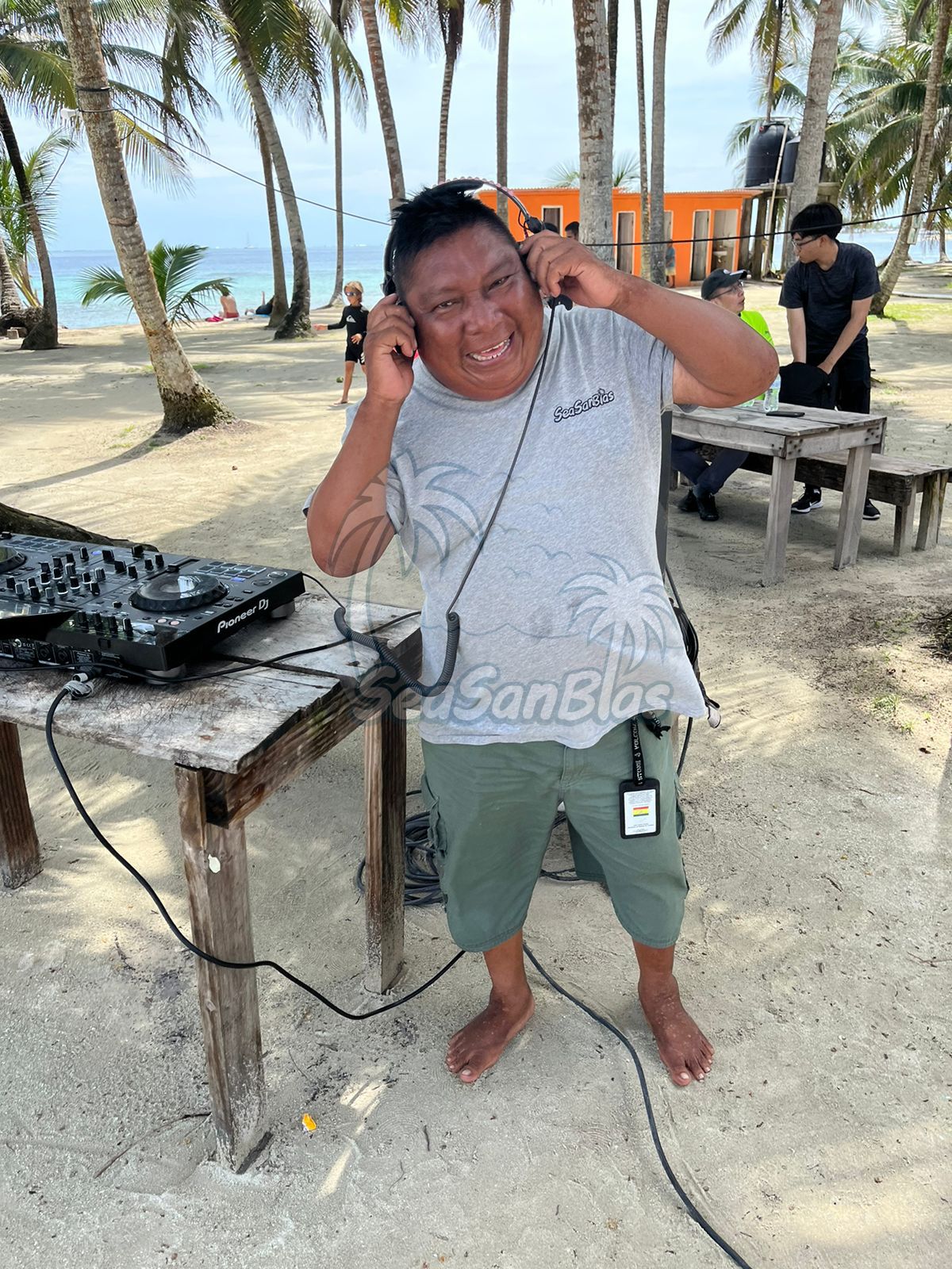 A man is standing on a beach wearing headphones.