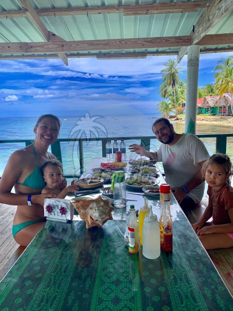 A group of people are sitting at a long table eating food. San Blas Islands Guna Yala San Blas Tours