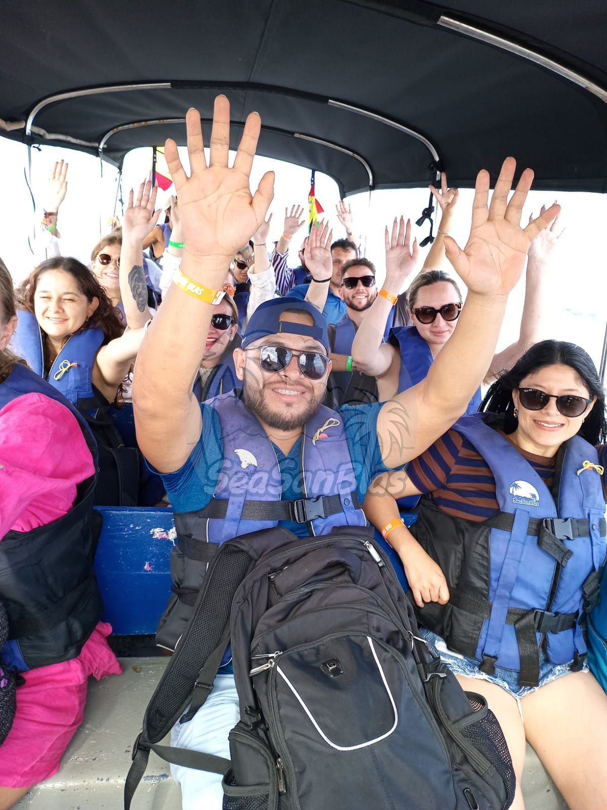 A group of people are sitting on a boat with their hands in the air. San Blas Islands Guna Yala San Blas Tours