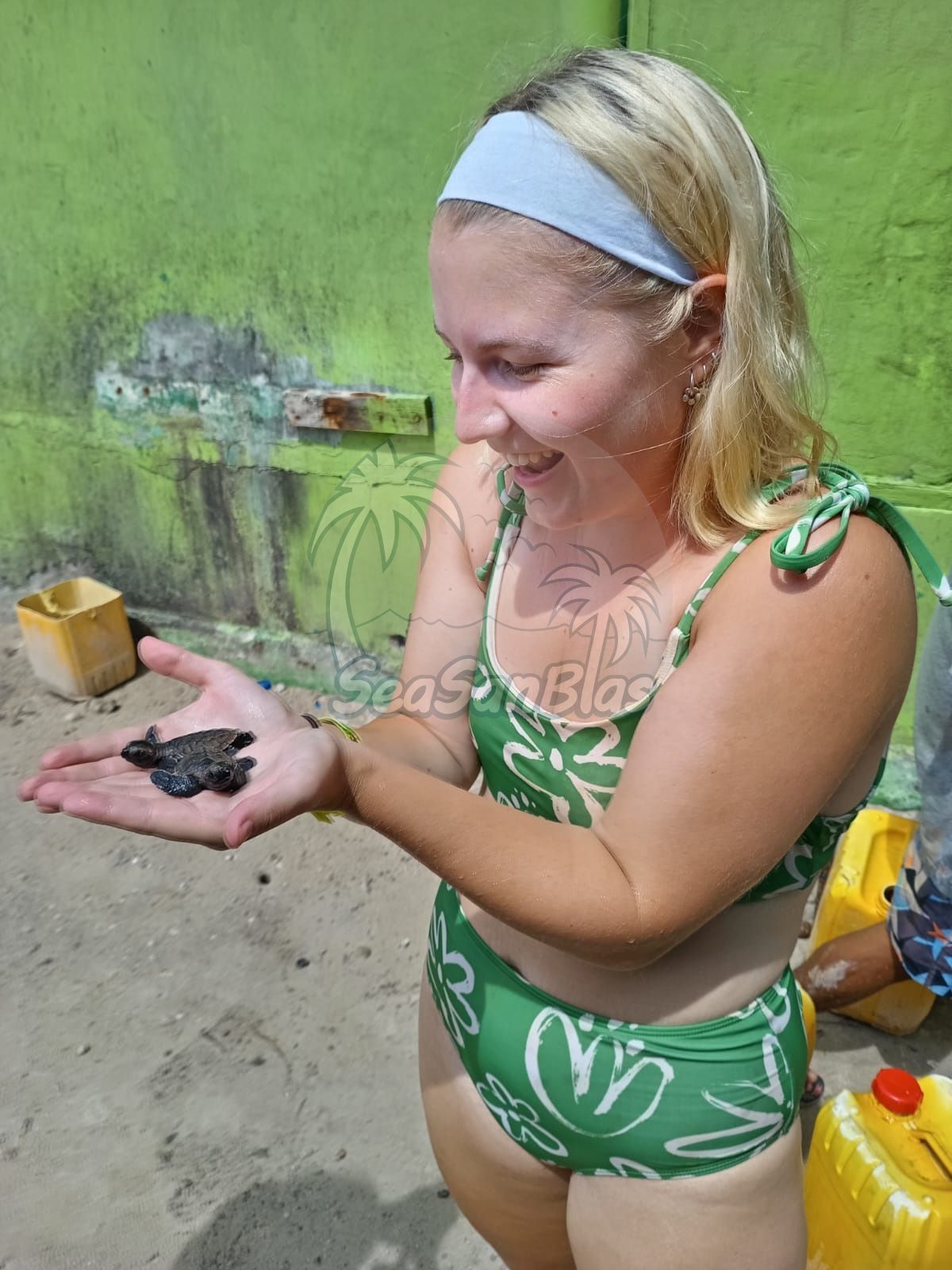 women in bathing suit holding two small baby sea turtles