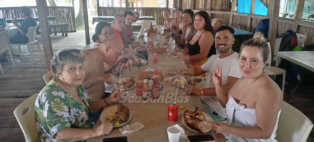 a group of people are sitting at a long table eating food .