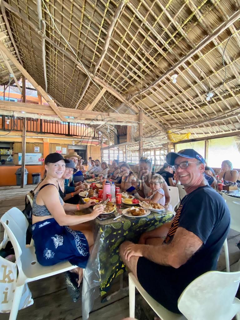 A group of people are sitting at a table eating food. San Blas Islands Guna Yala San Blas Tours