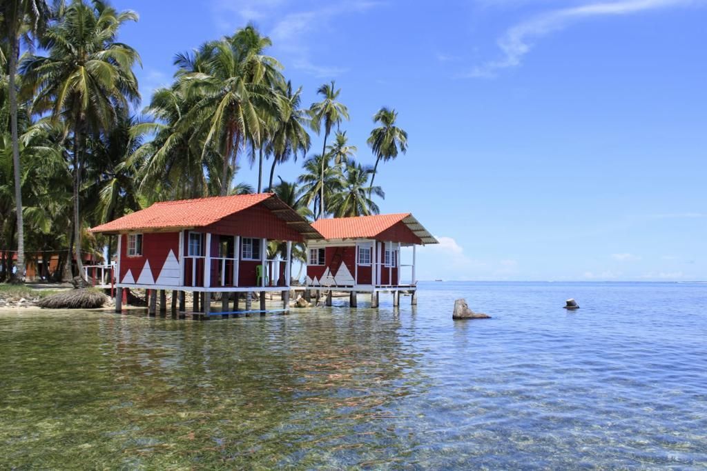 A couple of houses on stilts in the middle of the ocean.