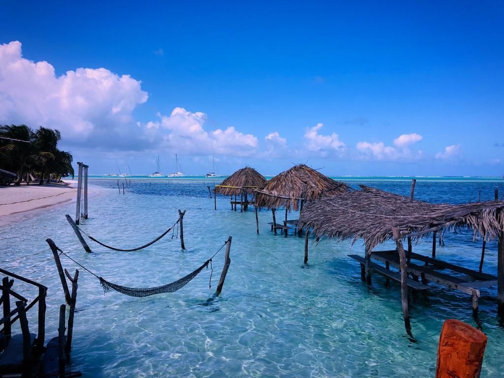 Two lounge chairs under an umbrella on a beach