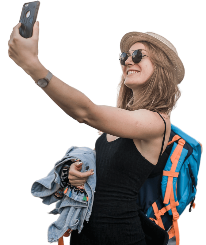 A woman with a backpack is taking a selfie with her phone