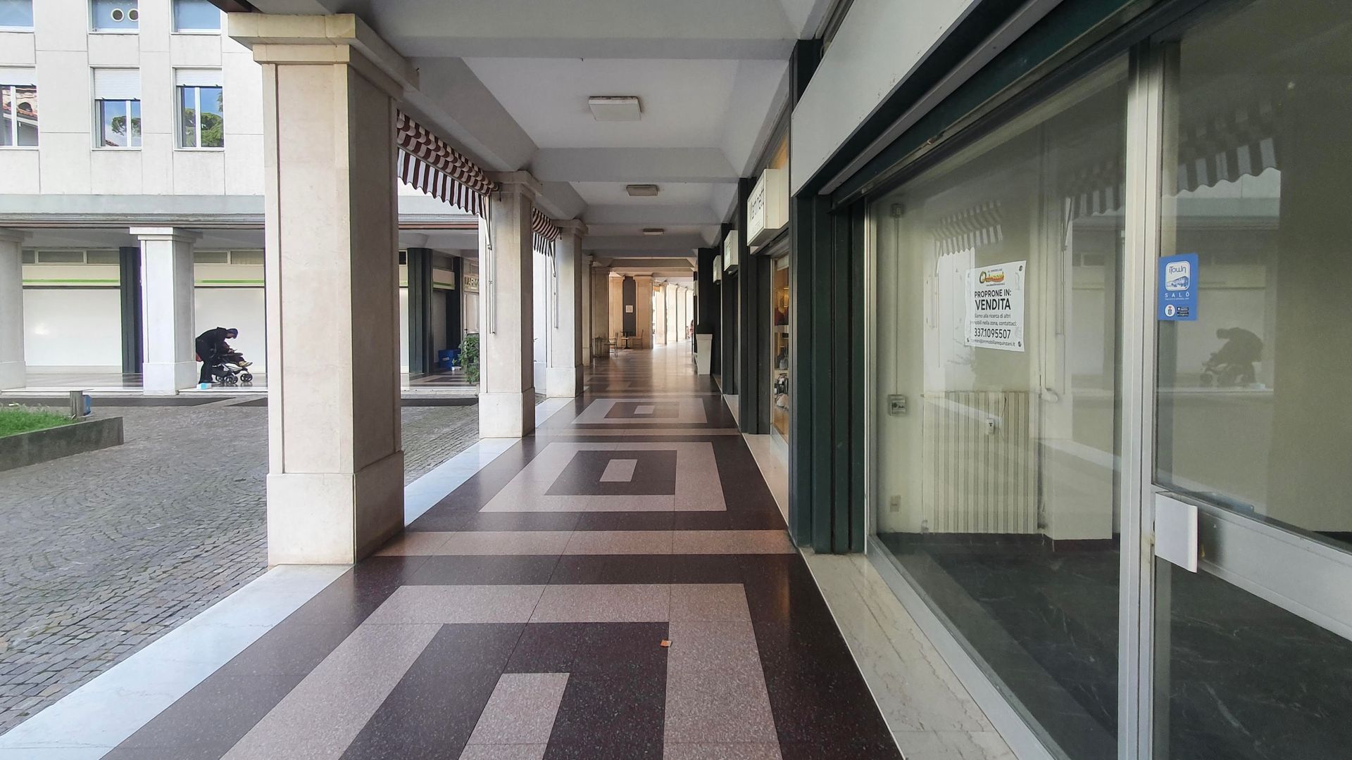 Un lungo corridoio tra due edifici con un motivo geometrico sul pavimento.