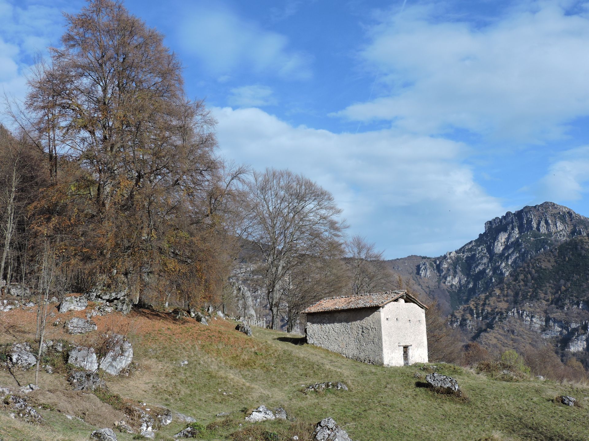 Una piccola casa è situata in cima a una collina erbosa tra le montagne.