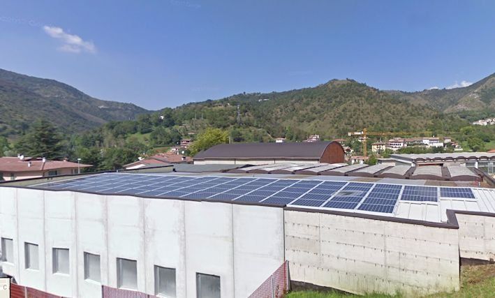 Un edificio con pannelli solari sul tetto e montagne sullo sfondo.