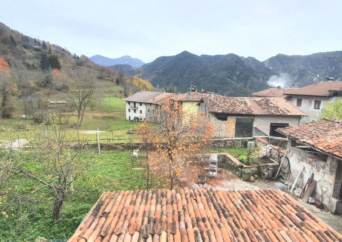 Un villaggio con il tetto di tegole rosse e le montagne sullo sfondo.