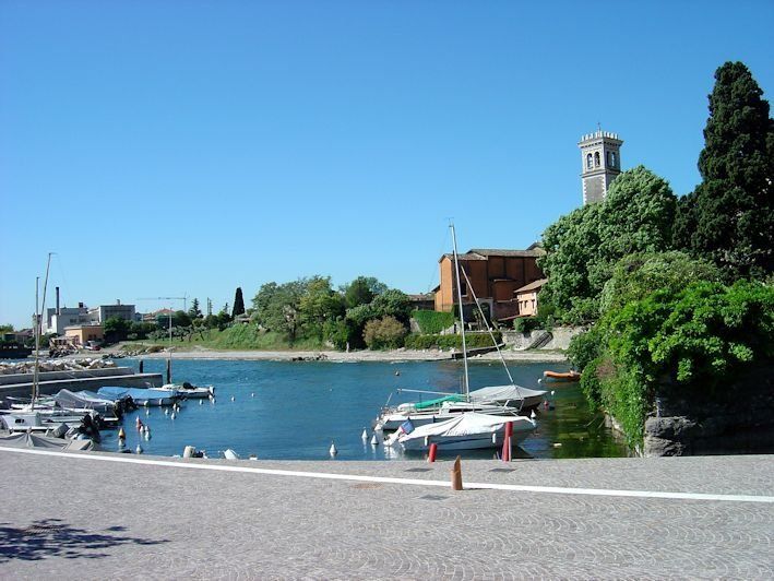 Uno specchio d'acqua con delle barche al suo interno e una chiesa sullo sfondo