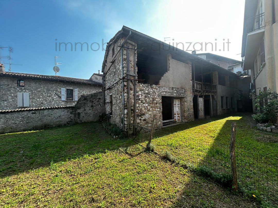 Un grande edificio in pietra si trova in mezzo a un lussureggiante campo verde.