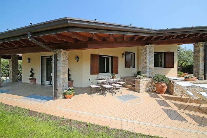 Una casa con un patio e tavoli e sedie davanti.