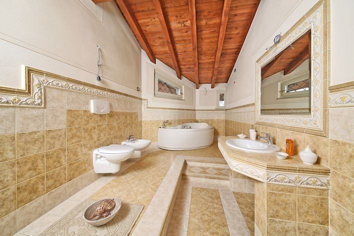 Un bagno con vasca, lavandino, water e specchio.