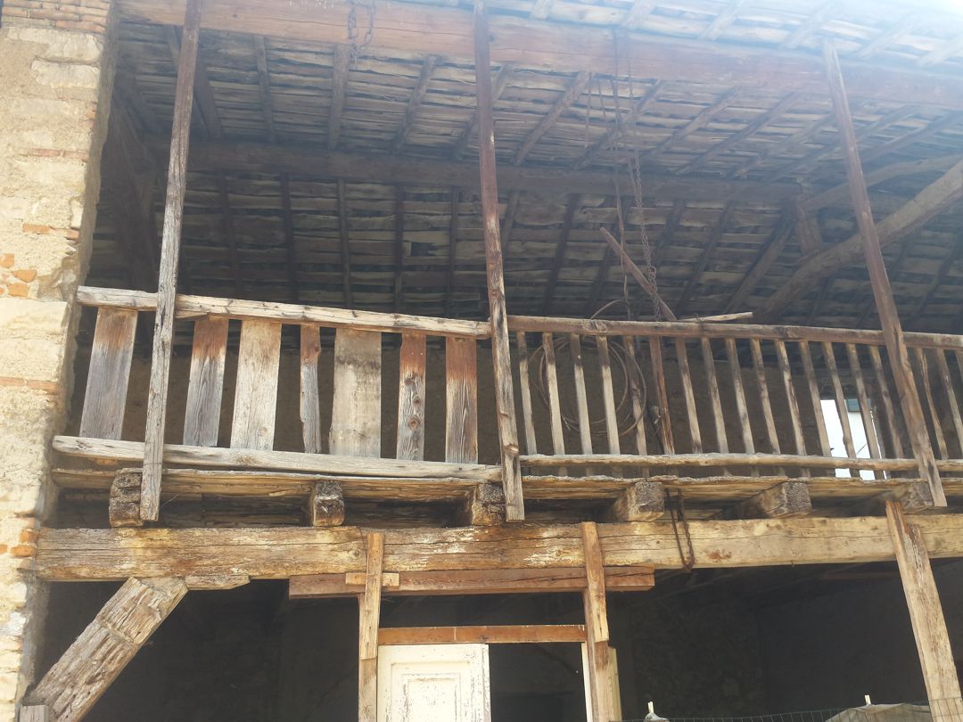 Un vecchio edificio con un balcone in legno al secondo piano