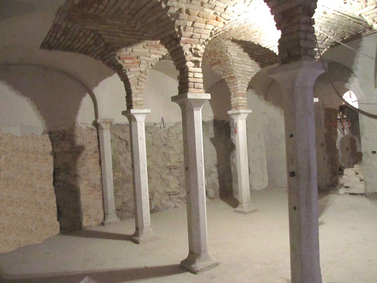 Una fila di colonne in una stanza con un soffitto in mattoni