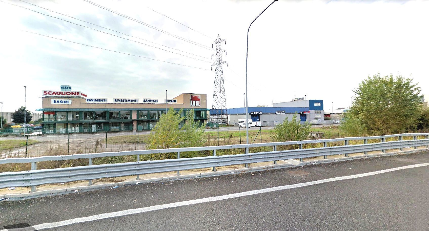 Un'autostrada con una recinzione e un edificio sullo sfondo.