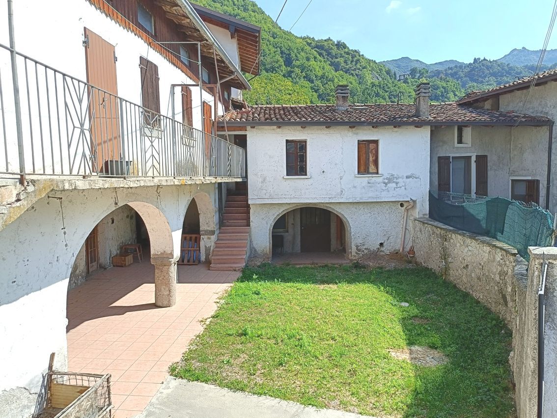 Un grande edificio bianco con un rigoglioso cortile davanti.