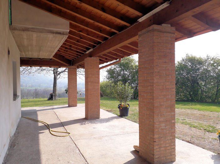 Un portico con colonne in mattoni e tetto in legno