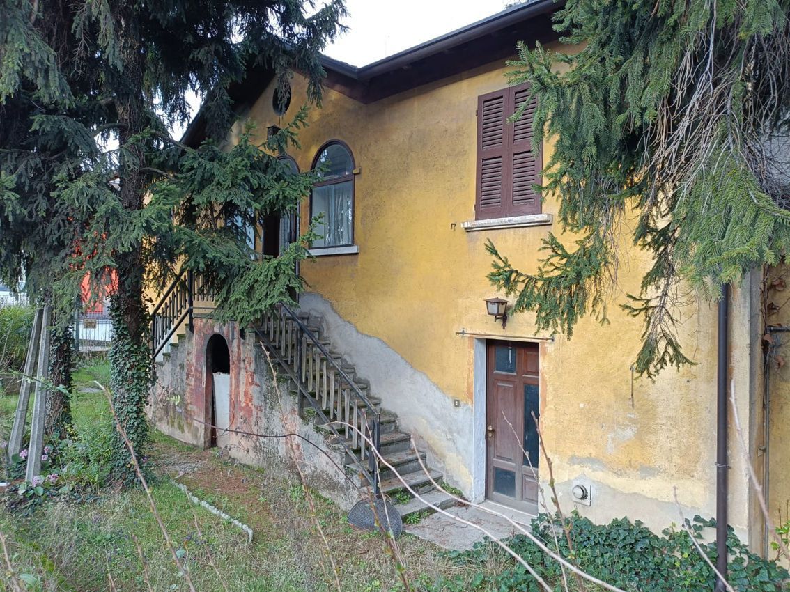 Una casa gialla circondata da alberi con delle scale che vi portano sopra.