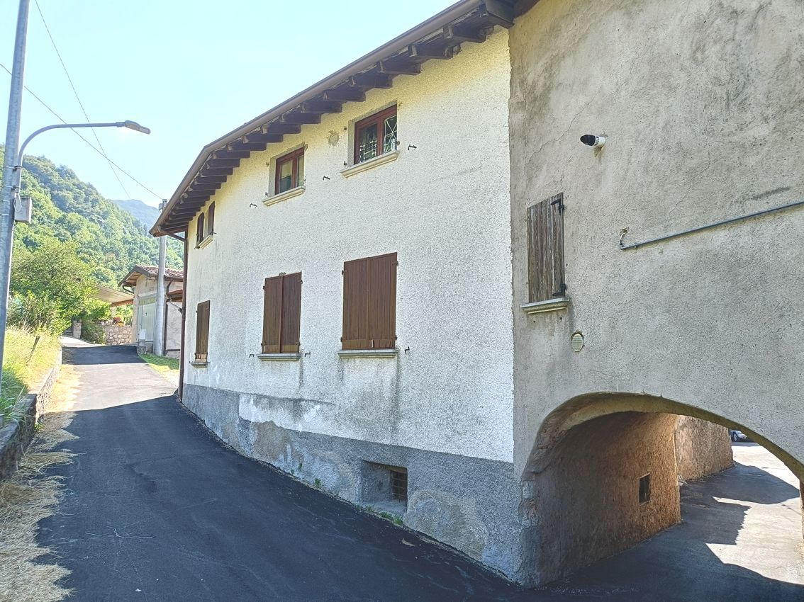 Un edificio bianco con persiane marroni alle finestre si trova accanto a una strada.