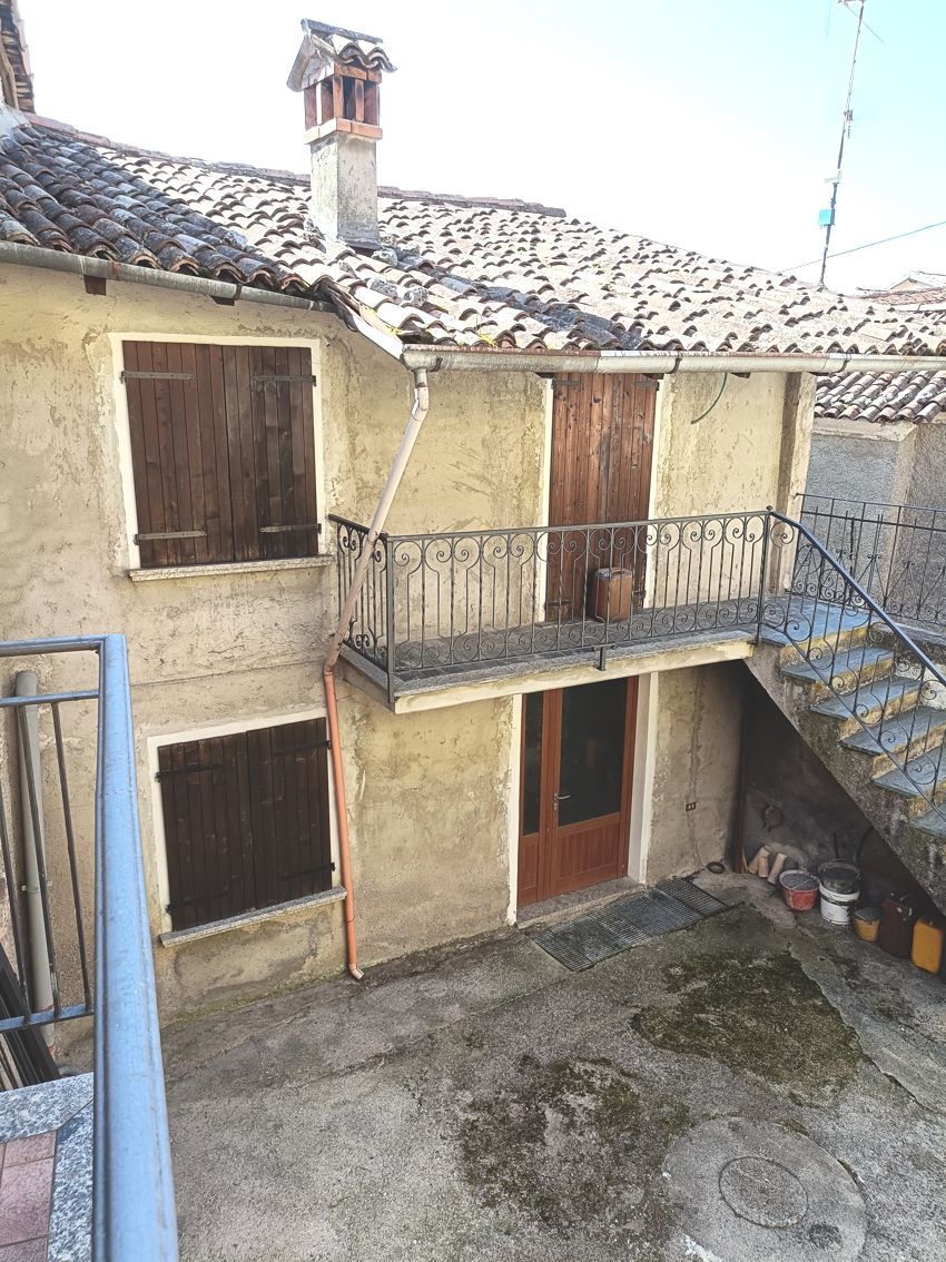 Una casa con un balcone e delle scale nel cortile sul retro.