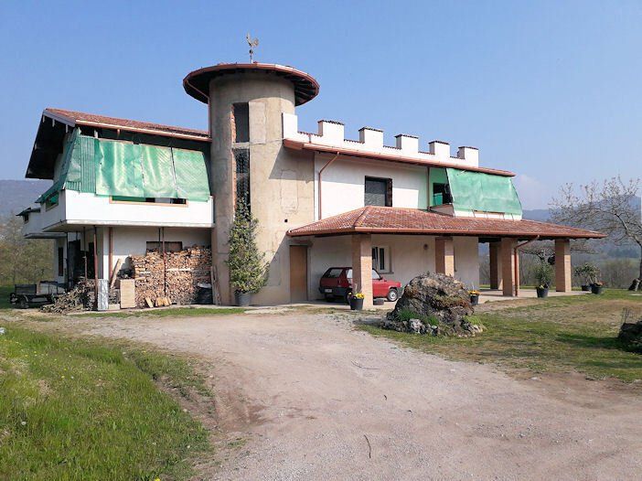 Una grande casa con un'auto rossa parcheggiata davanti