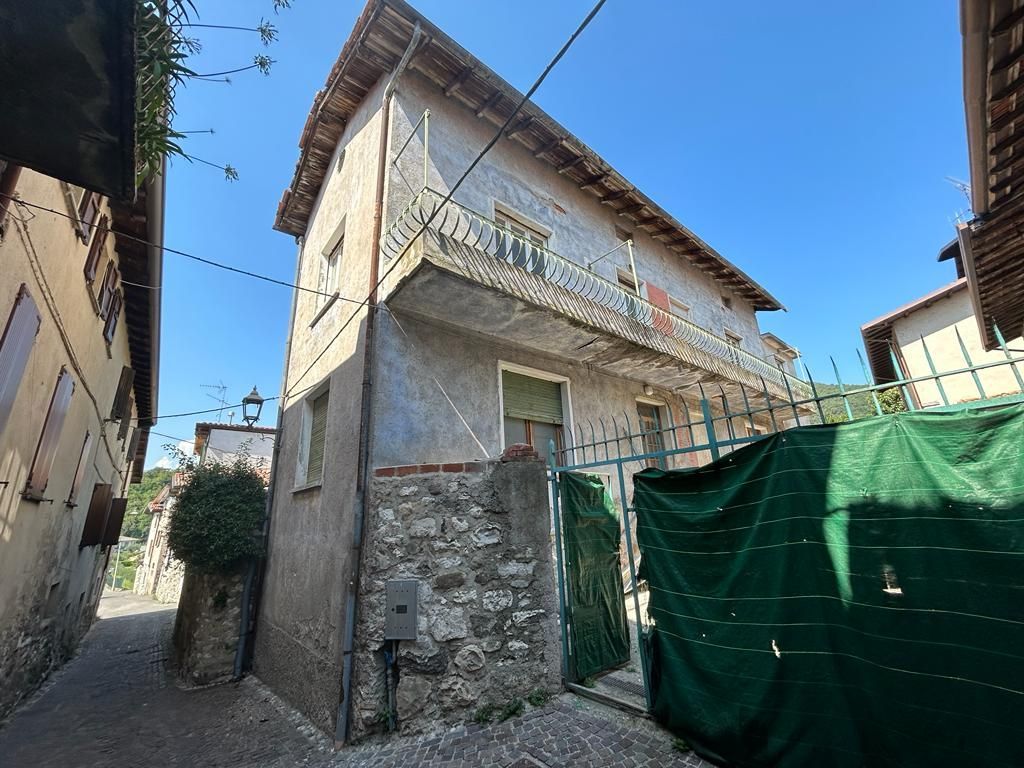 Un edificio con balcone è circondato da una recinzione verde.