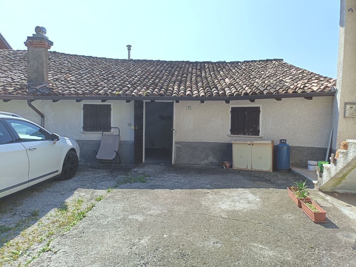 Un'auto bianca è parcheggiata davanti a una piccola casa con il tetto di tegole.